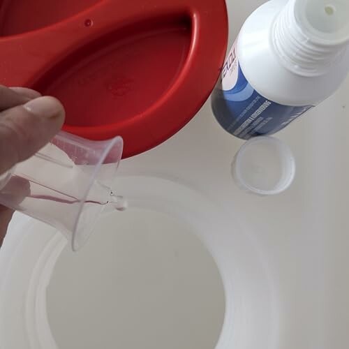 Personne versant du liquide dans un récipient.